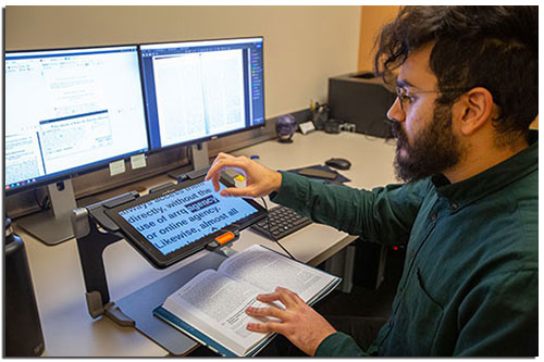 Man with a beard using screen reader accessible technology to access a website.
